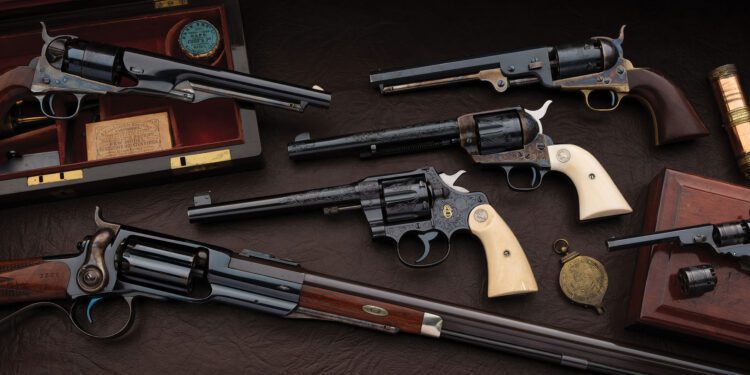 A collection of six vintage Colts with wooden and ivory grips, displayed on a dark surface with wooden cases and accessories, reminiscent of a firearm Concours d'Elegance.