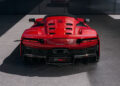 Rear view of a red hypercar parked on a concrete surface, with visible vents on the back and sleek taillights.