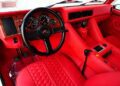 The image showcases the luxurious interior of a Lamborghini, featuring red leather upholstery, a black steering wheel, and a wood-accented dashboard with several gauges and controls. The incredible LM002 is now available for sale.