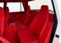 The interior of this 1990 Lamborghini showcases vibrant red leather seats, a matching console, and a clean, modern design. This rare Lamborghini LM002 is now for sale, offering an exquisite blend of luxury and style.