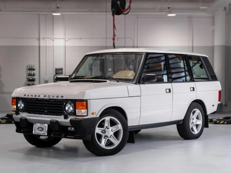 A white Range Rover Classic SUV, a nostalgic icon from the 90s, is parked in a garage with a clean, industrial interior.