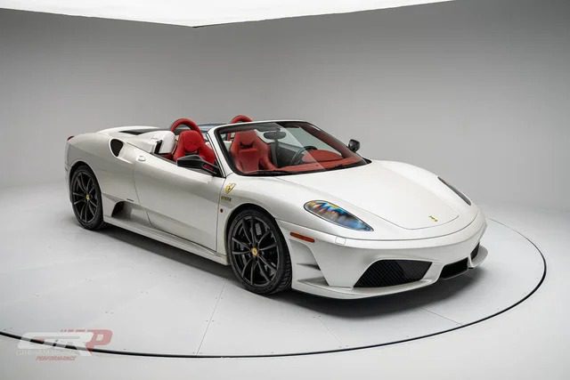 A stunning Ferrari 430 Scuderia convertible with black wheels and a sleek red interior is showcased in a studio setting, now available for sale.