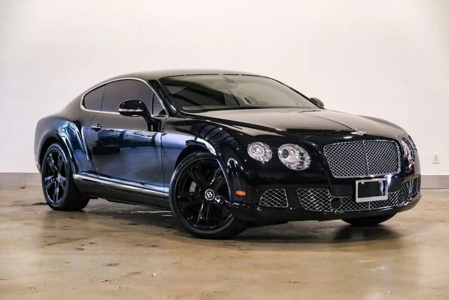 Bentley Continental GT Coupe, one of the best bentleys, stops on a concrete floor polished on a light wall in a light color.