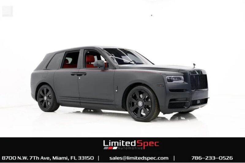 The Rolls-Royce Cullinan, a pinnacle of luxury SUVs, boasts a matte gray exterior with a striking red interior. Exhibited by Limited Spec Automotive in Miami, it stands majestically against a pristine white background.