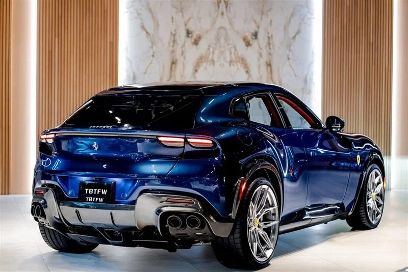 A blue Italian Super SUV is displayed in a showroom, capturing attention with its exquisite rear design and distinctive taillights.