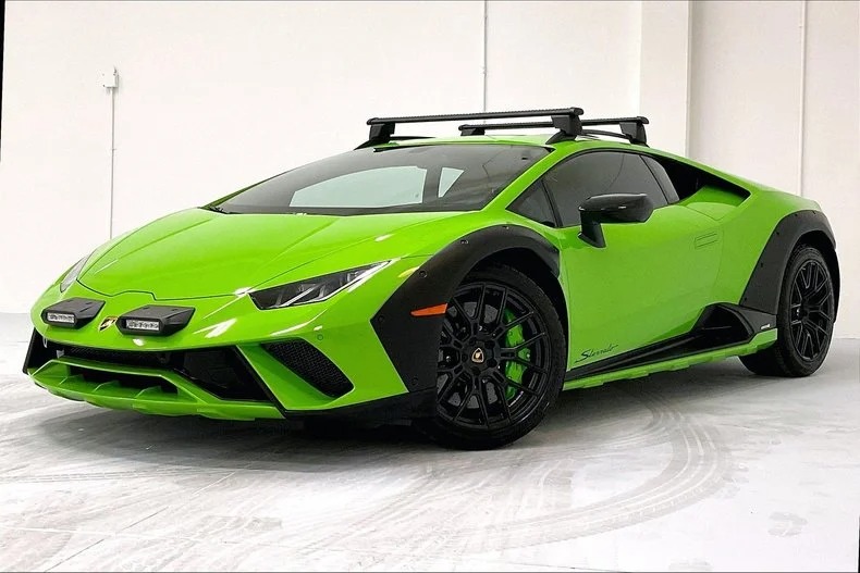 The vibrant green Lamborghini Huracán Sterrato, adorned with black accents and a stylish roof rack, boasts sleek design as it sits parked indoors. Ideal for those considering a Lamborghini purchase.