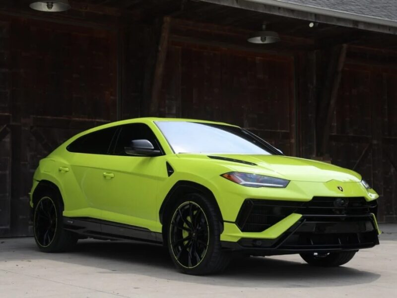 A bright green Lamborghini Urus is parked in front of a large wooden building, exemplifying the perfect blend of power and elegance that defines this Italian Super SUV.