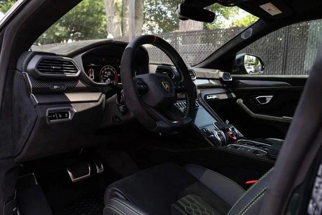 The interior of this Italian Super SUV exudes luxury, showcasing a sleek steering wheel, dashboard, and console with modern design and black accents reminiscent of a Lamborghini Urus.