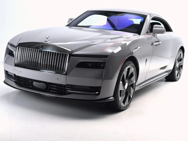 A sleek, gray electric ultra-luxe car with a shiny grille and modern design, parked in a well-lit studio setting.