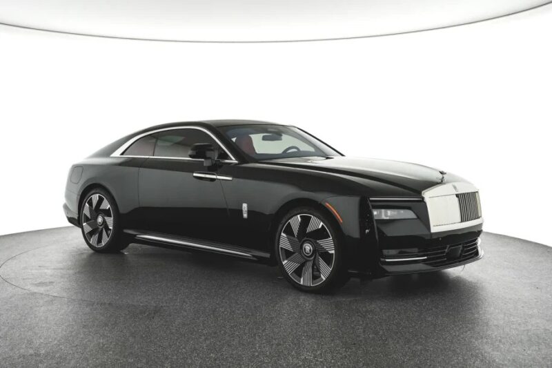 The Ultra-Luxe black coupe is showcased in a well-lit showroom, boasting a sleek design and distinctive alloy wheels. This Rolls-Royce Spectre captures the essence of elegance in an Electric Super Coupe.