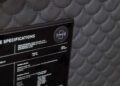 Close-up of a sleek black NFC Tech information plaque on a textured gray background with a scale-like pattern, reminiscent of the finely-tuned craftsmanship found in BRABUS Masterpiece Supercars.