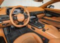 For sale: Experience the epitome of luxury in the 2025 Aston Martin Vanquish, boasting a stunning interior with tan leather upholstery, a sleek dashboard featuring a digital display, and a central console equipped with various controls.