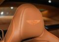 Close-up of a tan leather car seat with the Aston Martin logo embroidered in orange, reflecting the luxurious detailing found in the 2025 Vanquish by Exclusive Automotive Group.