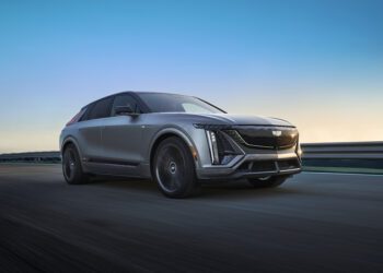 As the sun dips below the horizon, a sleek 2026 LYRIQ-V glides effortlessly along the road, embodying Cadillac's cutting-edge Electric V-Series Model beneath the clear evening skies.