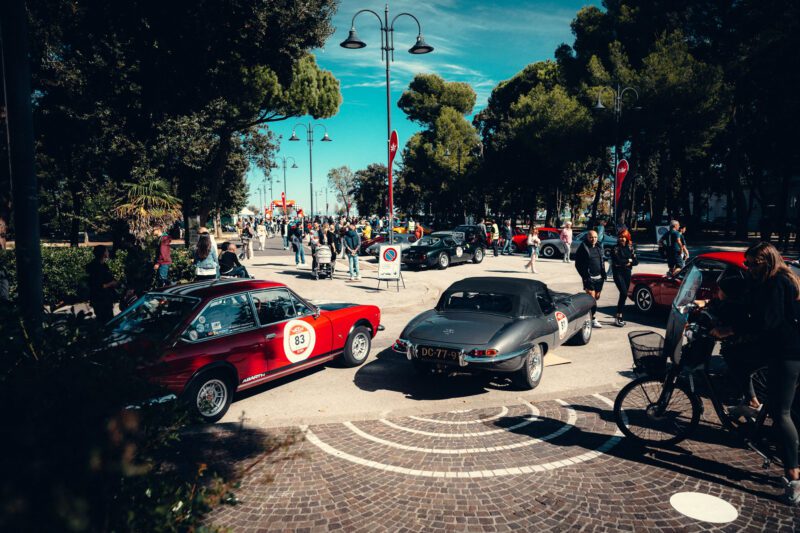 Amidst the clear blue sky, the Modena Cento Ore hosted a bustling classic car show filled with vintage gems. Enthusiasts admired a striking red and black car, capturing the essence of 2024’s automotive recap.