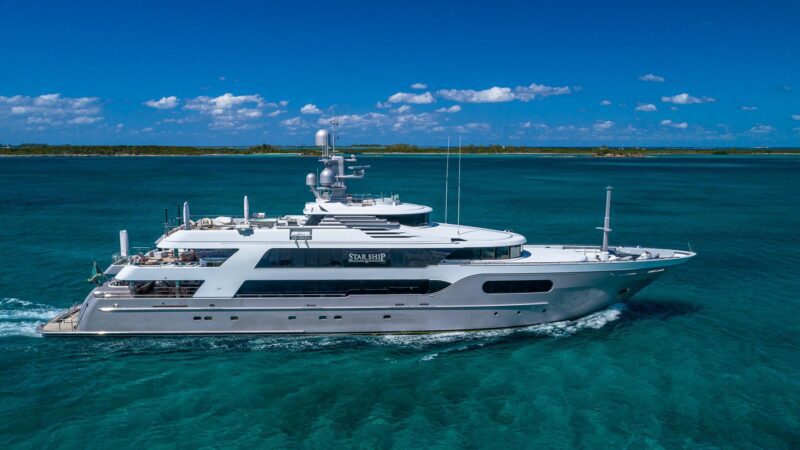 A large white yacht named "Star Ship" sails on clear turquoise waters under a blue sky with scattered clouds, embodying the elegance of luxury yachts showcased at the 2024 Fort Lauderdale International Boat Show.