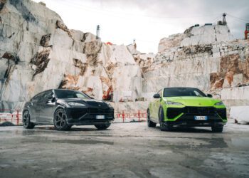 A black and a green Lamborghini SUV, including the Urus SE, stand majestically in a marble quarry with stone walls and a cloudy sky above, ready for the ultimate test drive event.