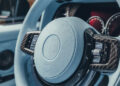 Close-up of a BRABUS steering wheel with a light blue leather cover and dark trim, perfectly complementing the custom dashboard in the background.