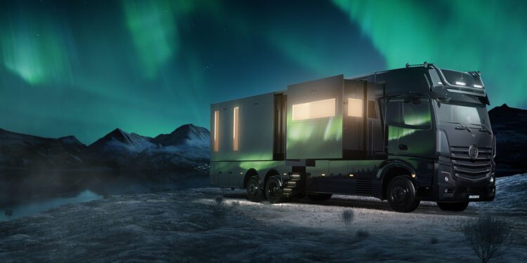 A BIG BOY 1200 truck with extended sections is parked in a snowy landscape under a vivid display of the Northern Lights.