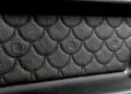 Close-up of a textured black leather surface with a scale pattern and circular BRABUS logos imprinted, reminiscent of the custom touches found in the Mercedes-AMG G 63 configurations.