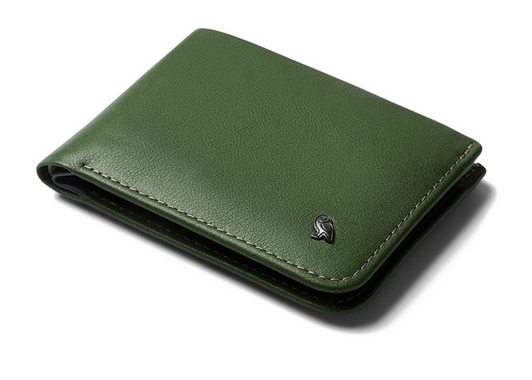 A closed, green leather wallet with a metallic emblem on the corner makes for an exquisite accessory in the Cooler Months, adding a touch of sophistication to any Fall Shopping Guide.