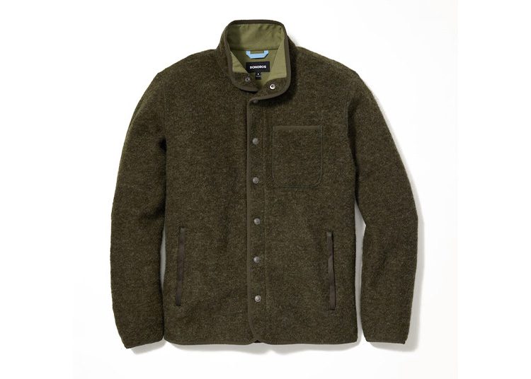 A dark green wool jacket with a standing collar and button closure, perfect for the cooler months. Featuring a chest pocket and two side pockets, it's showcased against a plain white background—a must-have piece from the Fall Shopping Guide.