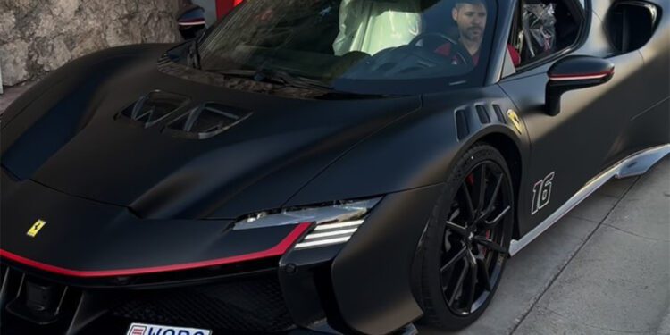 A man sits in a parked, black sports car with red accents, mirroring the sleek design of a Ferrari SF90 XX. The Monaco air complements his customized license plate, exuding an aura reminiscent of Charles Leclerc's racing finesse.