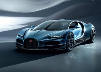 A sleek blue Bugatti sports car with a modern design is parked indoors, featuring next-century aerodynamic curves and black alloy wheels.