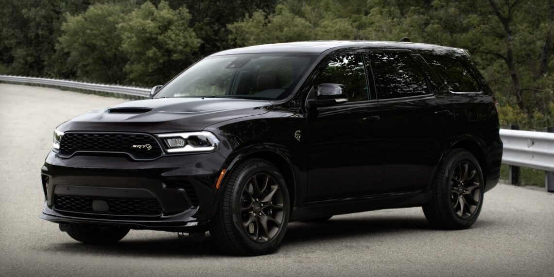 A Dodge Durango Brass Monkey SUV is parked on a road, showcasing its sleek design with trees in the background.