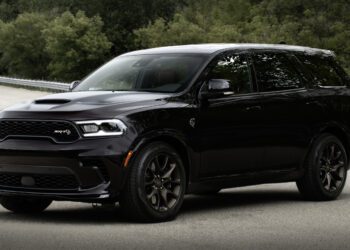 A Dodge Durango Brass Monkey SUV is parked on a road, showcasing its sleek design with trees in the background.