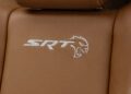 Close-up of a Dodge Durango SRT car seat with tan leather, featuring an embroidered "SRT" logo and a stylized cat head design, embodying the robust essence of HEMI Power.