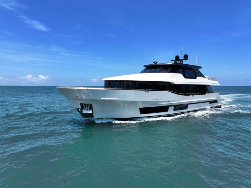 A modern white yacht, reflecting the pinnacle of luxury yachts, sails on a calm ocean under a clear blue sky, reminiscent of what awaits at the 2024 Fort Lauderdale International Boat Show.