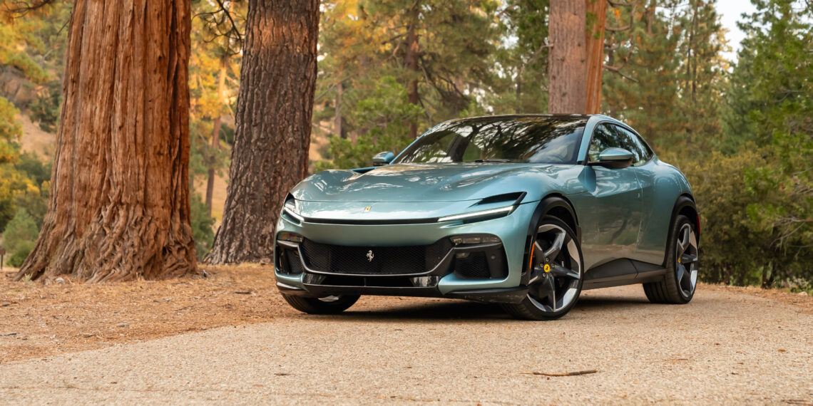 A sleek, green sports car parked on a forest road between tall trees.