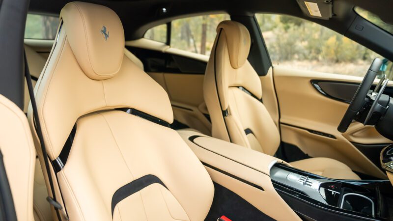 Interior of a luxury car with tan leather seats, a sleek center console, and a prominent logo on the headrests.