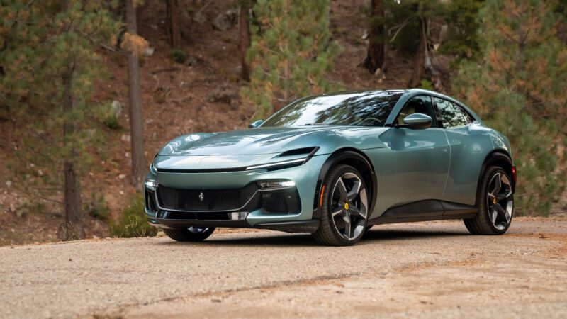 A sleek, green sports car parked on a road with a forested background.