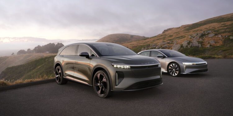 Two sleek, modern cars, including the 2025 Lucid Gravity, parked majestically on a scenic road with hills and a cloudy sky overhead.