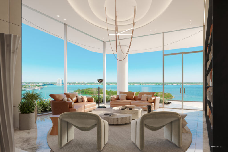 Modern living room with beige and brown furniture, large windows, and a view of a body of water. Ceiling lights hang over the circular coffee table, adding elegance to this exquisite space in Pagani Residences.