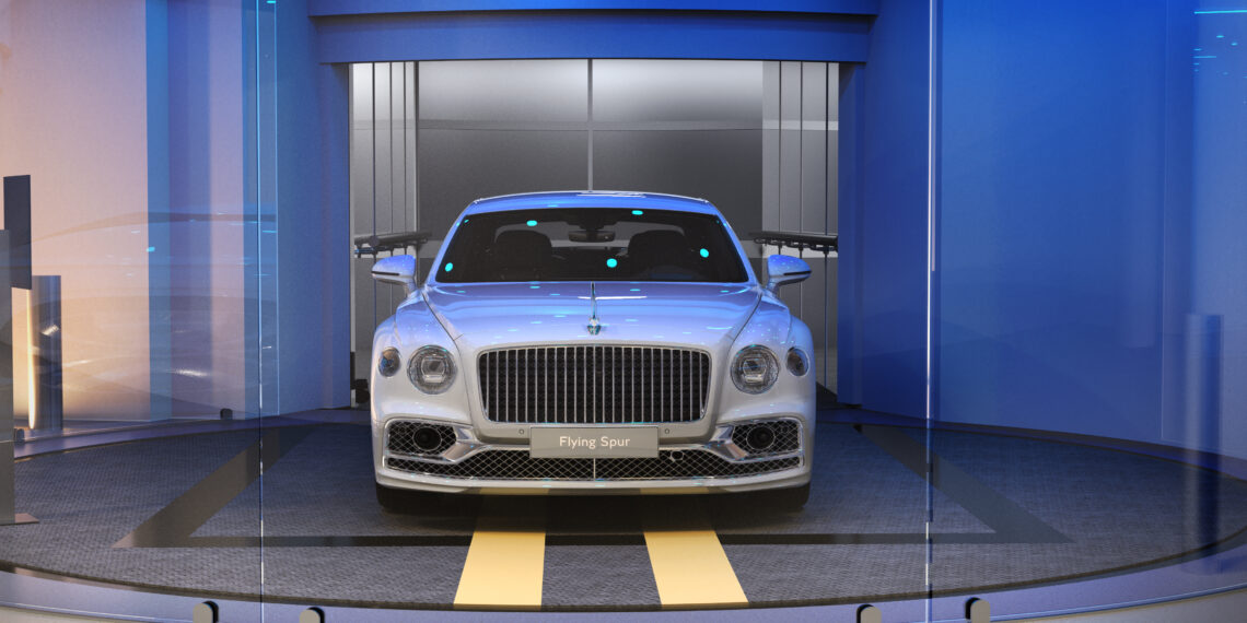 A luxury white sedan graces the modern showroom, bathed in elegant blue lighting. The scene exudes sophistication, reminiscent of the opulence found at Bentley Residences, where even the car keys are a testament to exquisite design.