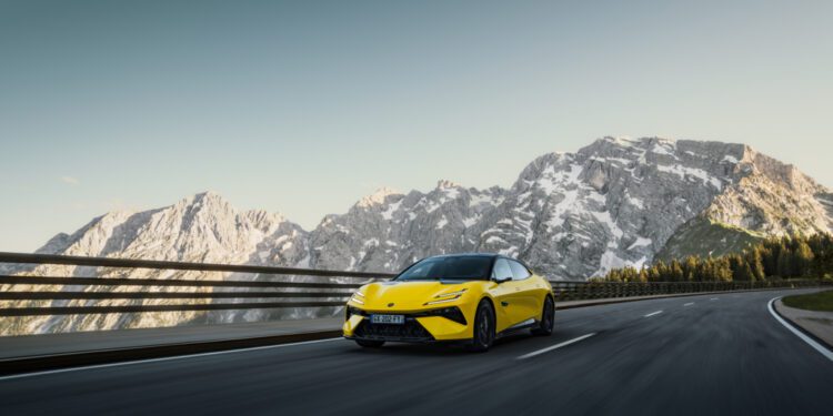 A yellow sports car zips along a mountain highway, with snow-capped peaks framed against a clear sky—a scene that feels as exhilarating as an auto draft on an open road.