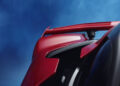 Close-up of a red Ferrari sports car spoiler against a blue sky background, capturing the essence of hypercar elegance.