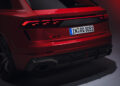 Rear view of a powerful red Audi RS Q8 Performance, showcasing its striking taillights and rear bumper details, with the visible license plate underscoring its prestige as an Audi Sport model.