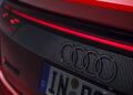 Close-up of the rear of a red Audi e-tron GT, showcasing the Audi logo and European license plate, alongside a sleek taillight design reminiscent of Audi Sport aesthetics.