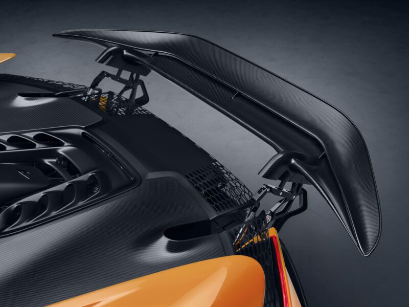 Close-up of a carbon fiber rear spoiler on the McLaren W1, featuring intricate details and a metallic orange finish.