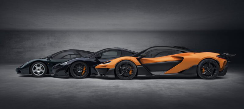 Three sleek, modern sports cars, including a stunning McLaren W1, are parked side by side in a dimly lit showroom. Captured in elegant photos, these machines boast impressive specs that highlight their cutting-edge design and engineering prowess.