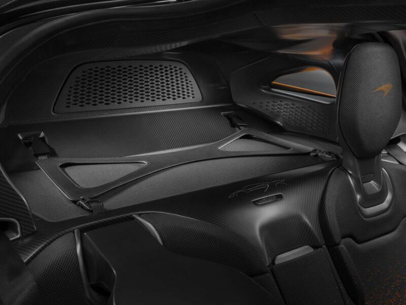 Experience the luxurious interior of a McLaren W1, featuring a sleek, carbon fiber design with a mesh-covered compartment and a branded headrest.