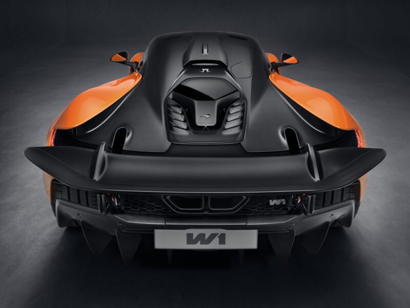 Rear view of a McLaren W1 sports car with a large rear spoiler, sleek curves, and a visible engine cover proudly labeled 'W1.'