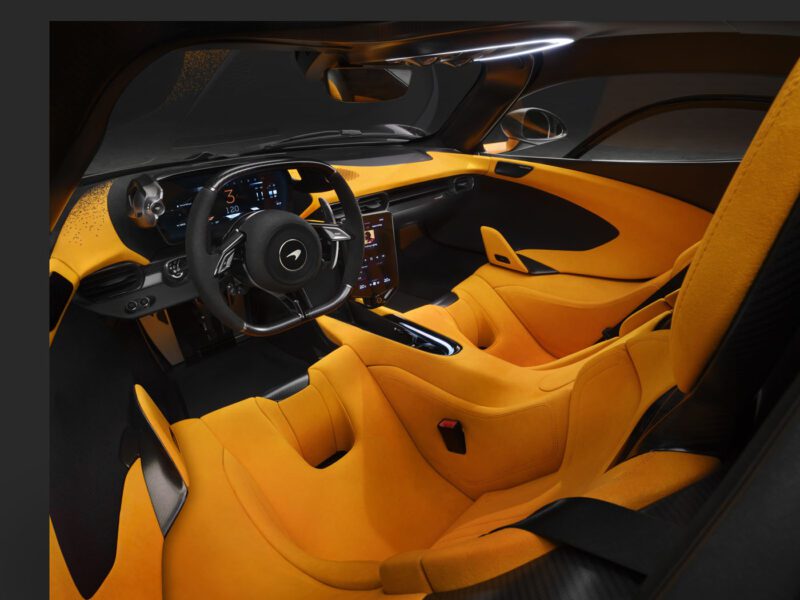 Interior view of the McLaren W1 luxury sports car featuring yellow and black seats, a steering wheel, and a central touchscreen display.