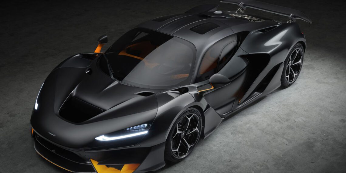 A sleek, black McLaren W1 sports car with aerodynamic curves, highlighted by yellow accents, is seen from above in a dimly lit environment.