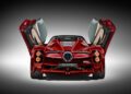 A red Pagani sports car with gull-wing doors open, viewed from the rear. This stunning Zonda features prominent taillights and a quad exhaust system, embodying the essence of automotive excellence.