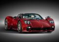 A sleek, red Pagani Utopia Roadster with a polished finish and distinctive headlights, shown against a neutral gradient background.